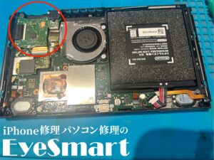 分解されたNintendo Switchの内部。左上に赤い丸で囲まれたゲームカードスロット部分が交換対象です。基板やバッテリー、冷却ファンなどの部品が見えます。画面下部には『iPhone修理パソコン修理のEyeSmart』のロゴが記載されています。
