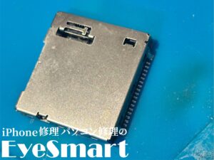 Nintendo Switchのゲームカードスロット部分のみを取り外した状態。基板から分離された金属製のスロットが青いマットの上に置かれています。画面下部には『iPhone修理パソコン修理のEyeSmart』のロゴが記載されています。